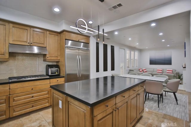 kitchen with appliances with stainless steel finishes, decorative backsplash, a center island, and decorative light fixtures