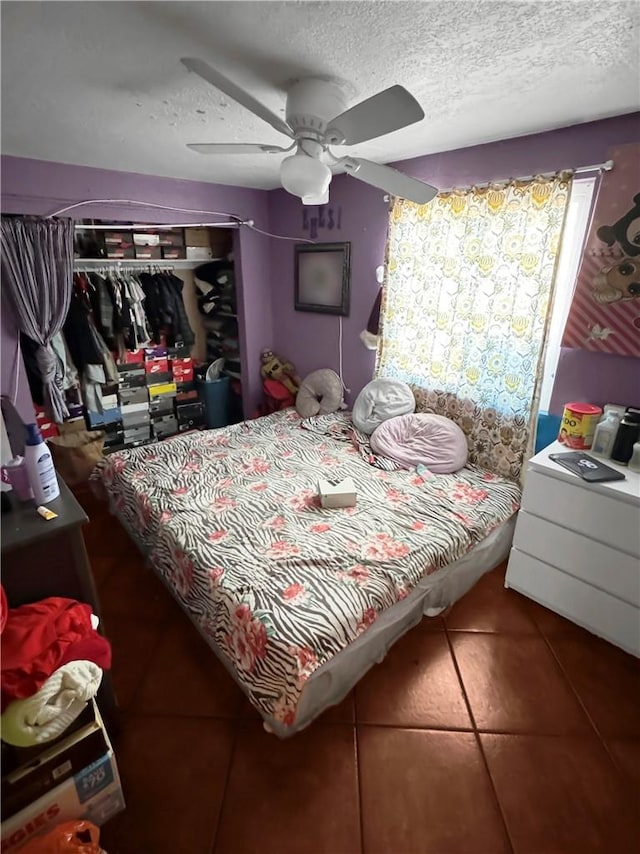 tiled bedroom featuring ceiling fan and a textured ceiling