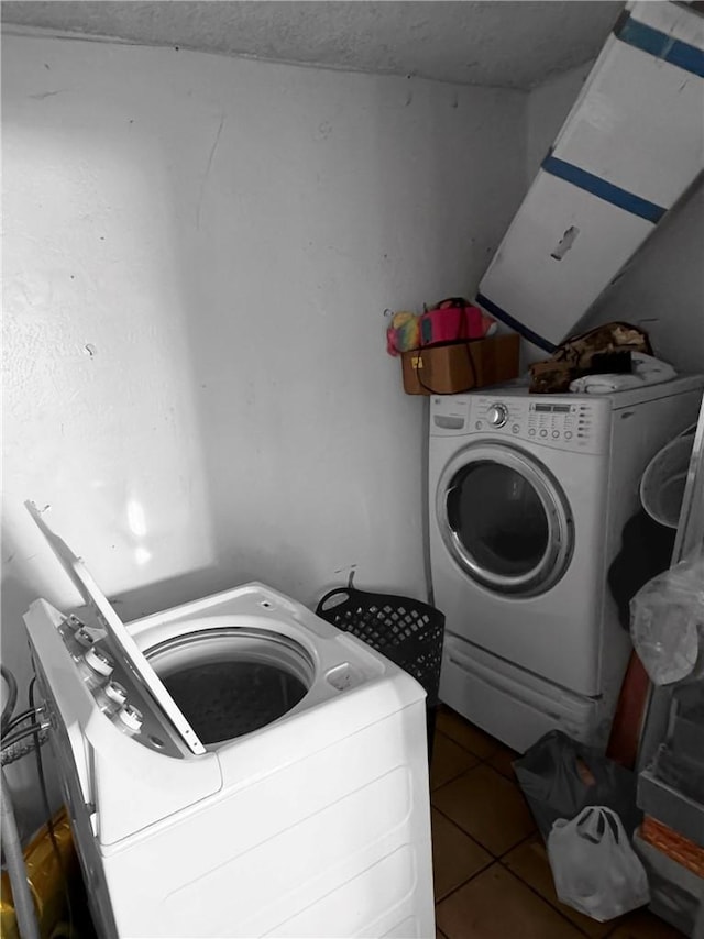 laundry area with dark tile patterned flooring and washer and dryer