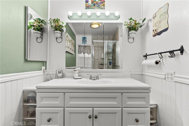 bathroom with a shower with shower door, vanity, and ornamental molding