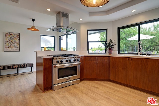 kitchen with high end stainless steel range oven, pendant lighting, island range hood, and light wood-type flooring