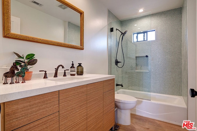 full bathroom with vanity, hardwood / wood-style flooring, toilet, and tiled shower / bath