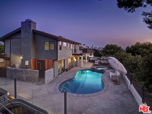 pool at dusk featuring an in ground hot tub and a patio area