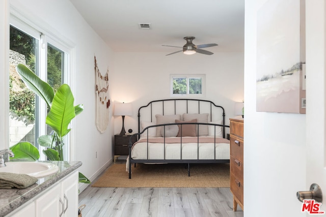 bedroom featuring light hardwood / wood-style floors, sink, multiple windows, and ceiling fan