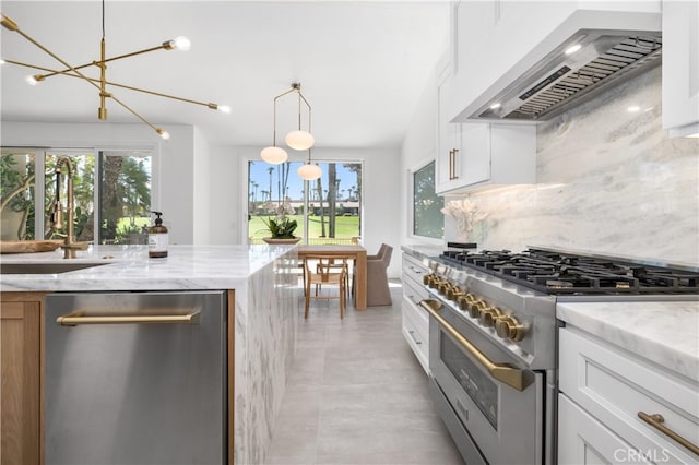 kitchen with light stone countertops, white cabinets, wall chimney exhaust hood, stainless steel appliances, and decorative backsplash