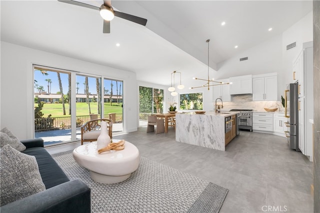 living room featuring ceiling fan with notable chandelier, high vaulted ceiling, and sink