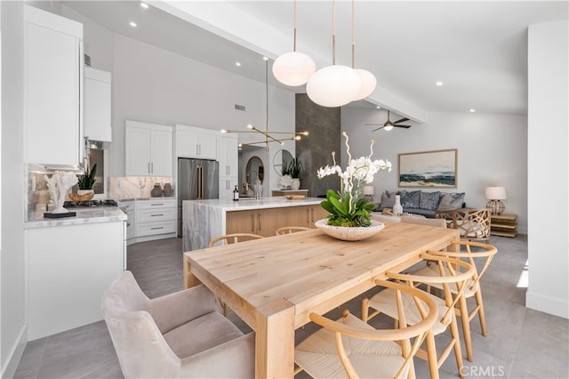 dining area featuring ceiling fan, sink, high vaulted ceiling, and beamed ceiling