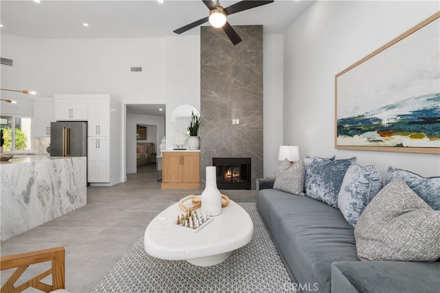 living room featuring ceiling fan, a high ceiling, and a high end fireplace