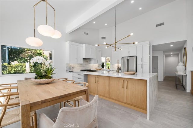 kitchen with decorative light fixtures, white cabinets, a large island, and appliances with stainless steel finishes