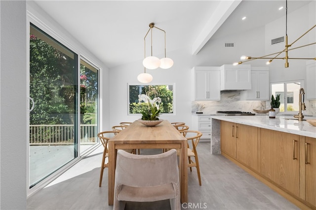 dining space featuring sink, a wealth of natural light, lofted ceiling, and an inviting chandelier