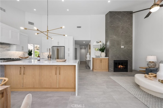 kitchen with white cabinetry, appliances with stainless steel finishes, a spacious island, a premium fireplace, and pendant lighting