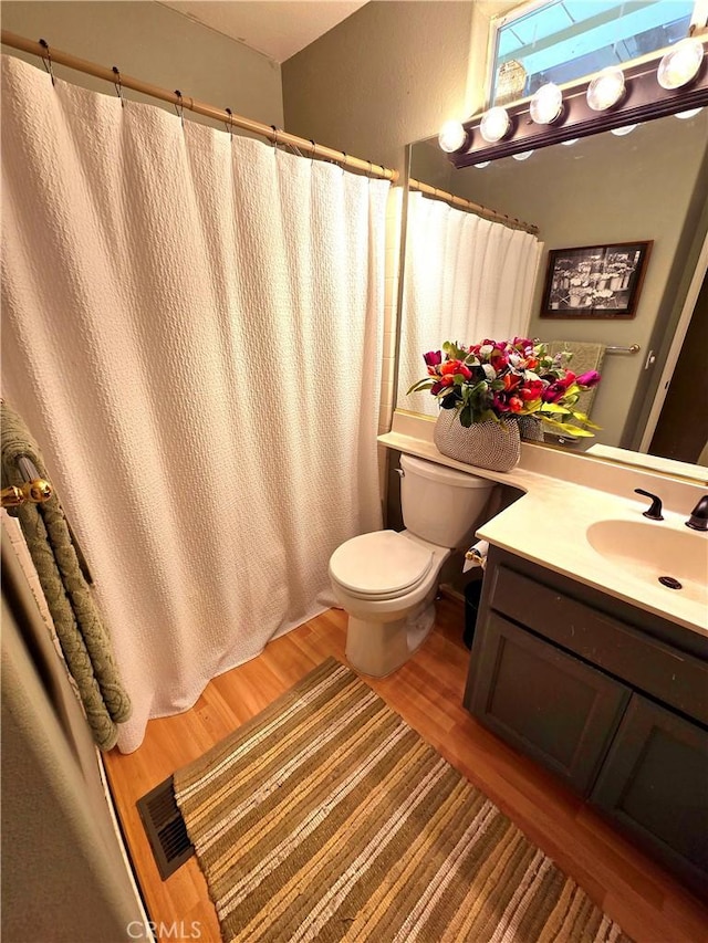 bathroom featuring toilet, vanity, and hardwood / wood-style flooring