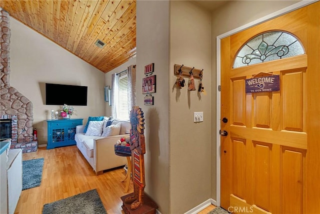 entryway featuring light hardwood / wood-style floors, wooden ceiling, lofted ceiling, and a fireplace