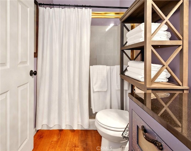 bathroom featuring hardwood / wood-style flooring, toilet, and a shower with curtain