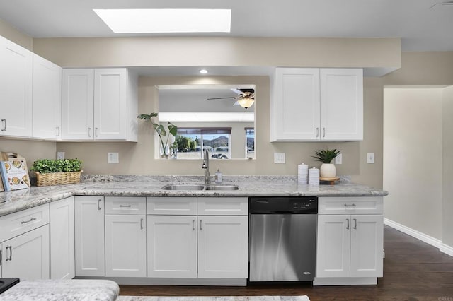 kitchen with white cabinets, dishwasher, a skylight, light stone counters, and sink