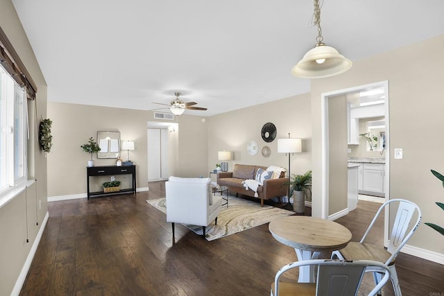 living room featuring dark wood-type flooring, ceiling fan, and a healthy amount of sunlight