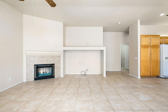 unfurnished living room featuring ceiling fan, light tile patterned flooring, and a fireplace