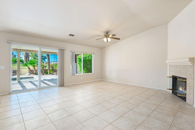 unfurnished living room featuring ceiling fan, light tile patterned floors, lofted ceiling, and a tiled fireplace