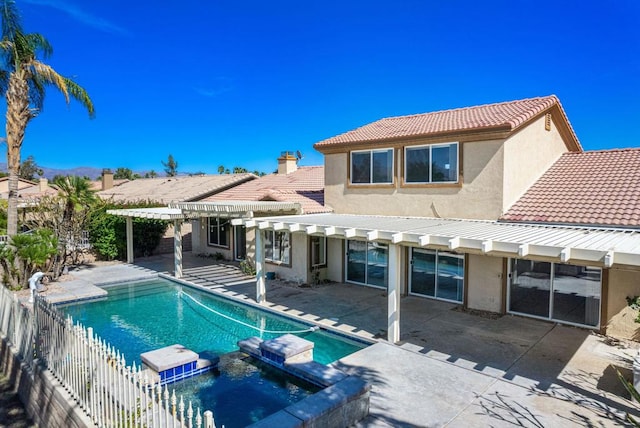 rear view of house with a swimming pool with hot tub, a pergola, and a patio