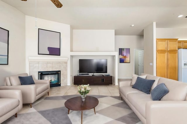 tiled living room with ceiling fan and a fireplace