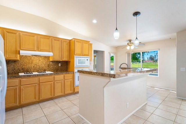 kitchen featuring decorative backsplash, white appliances, lofted ceiling, and a kitchen island with sink