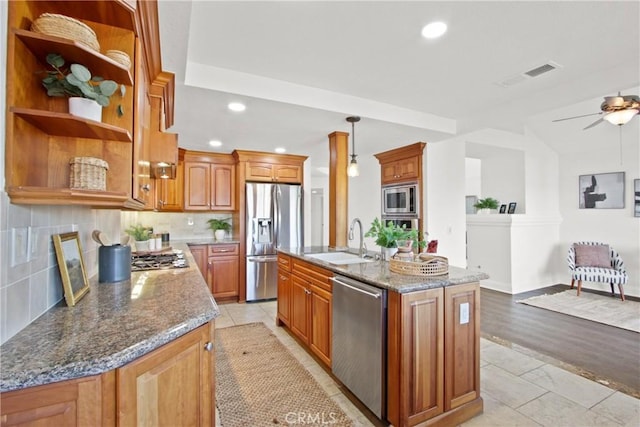 kitchen featuring sink, appliances with stainless steel finishes, a kitchen island with sink, and dark stone counters