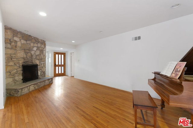 unfurnished living room featuring light wood-type flooring and a stone fireplace