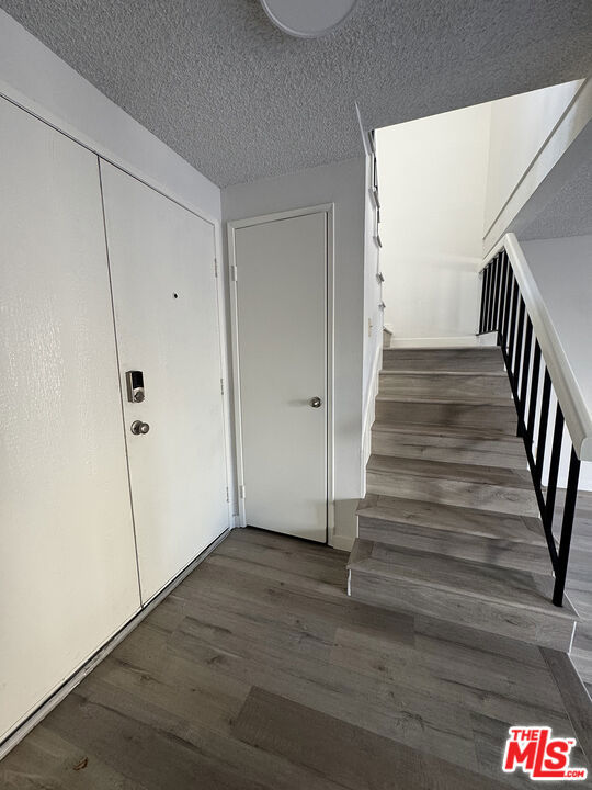 staircase featuring wood-type flooring and a textured ceiling