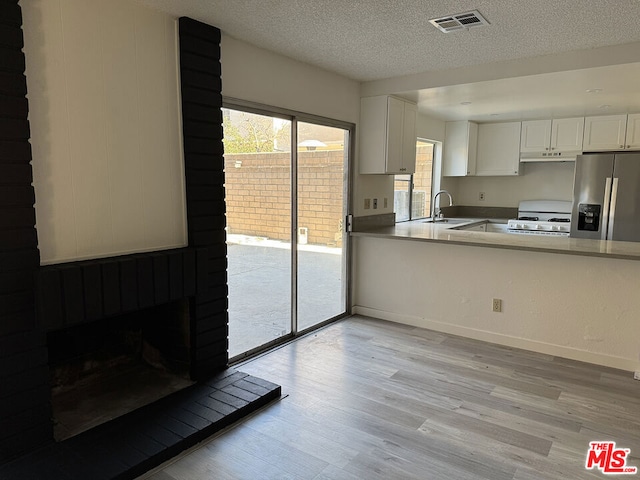 kitchen featuring white cabinetry, sink, stainless steel refrigerator with ice dispenser, white stove, and light wood-type flooring