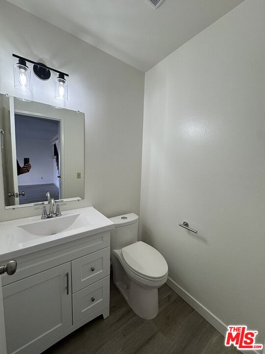 bathroom with vanity, wood-type flooring, and toilet