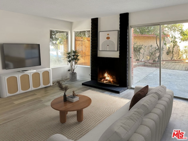 living room with a fireplace, light hardwood / wood-style floors, and a textured ceiling