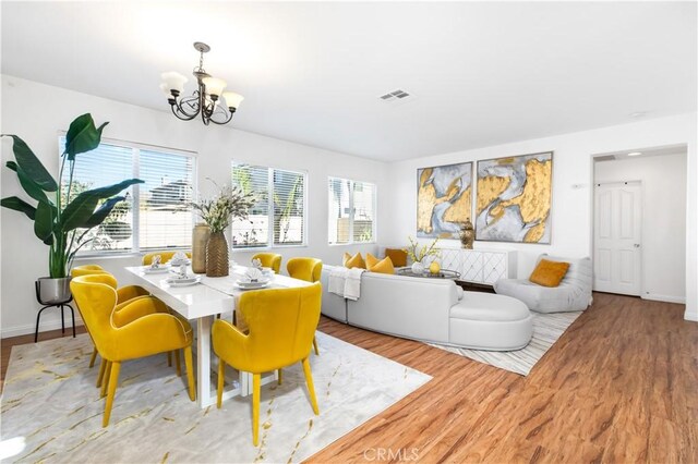 dining area with light wood-type flooring and an inviting chandelier