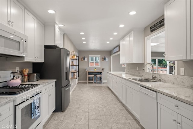 kitchen with baseboards, recessed lighting, white cabinets, white appliances, and a sink