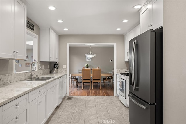 kitchen featuring white range with gas cooktop, a sink, white cabinetry, stainless steel fridge, and dishwasher