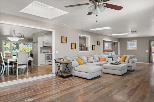 living room featuring ceiling fan, wood-type flooring, and a skylight