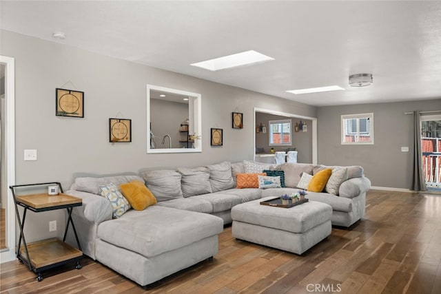 living area featuring a skylight, wood finished floors, and baseboards