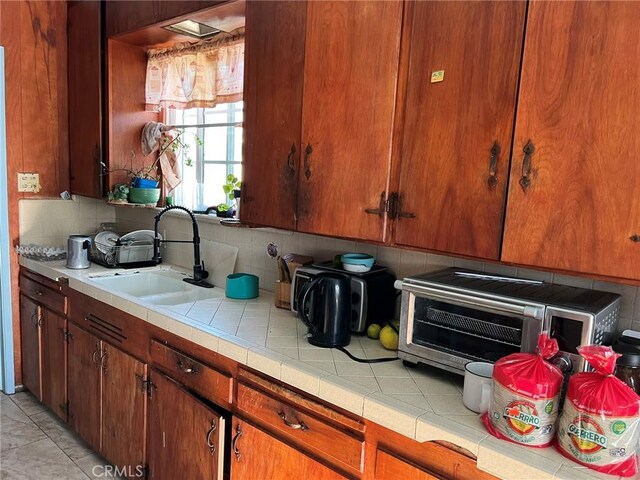 kitchen with backsplash, sink, tile countertops, and light tile patterned flooring