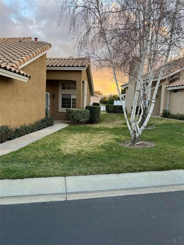 property exterior at dusk with a lawn