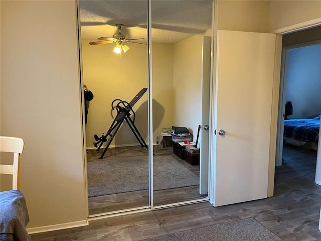 unfurnished bedroom with a textured ceiling, ceiling fan, dark hardwood / wood-style flooring, and a closet