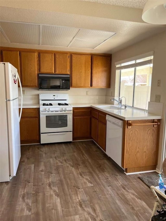 kitchen with dark hardwood / wood-style floors, sink, white appliances, and a textured ceiling