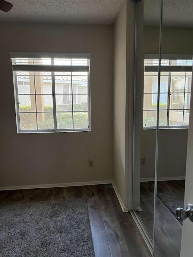 spare room featuring dark hardwood / wood-style flooring and a textured ceiling