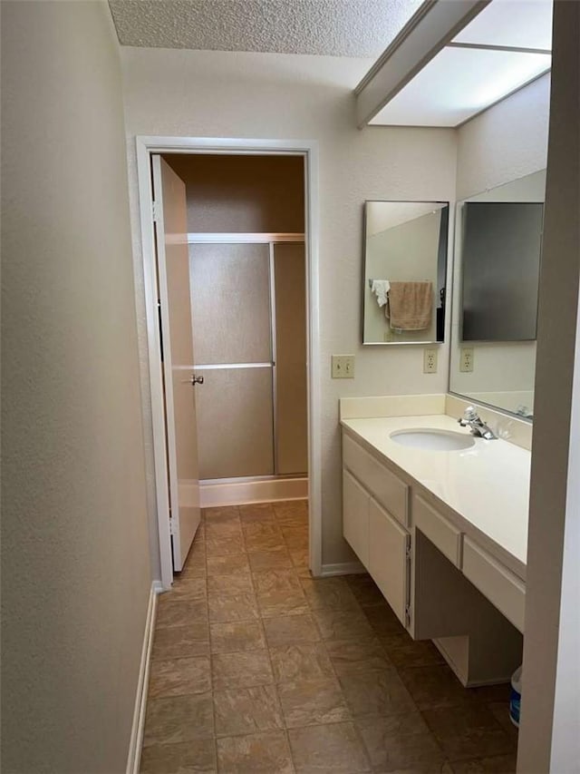 bathroom with a textured ceiling, a shower with door, and vanity