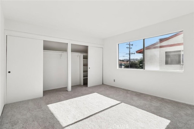 unfurnished bedroom featuring two closets and light colored carpet