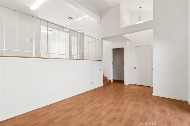 unfurnished living room featuring beam ceiling and light wood-type flooring