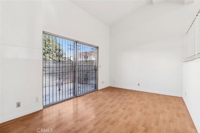 unfurnished room with light hardwood / wood-style flooring and high vaulted ceiling