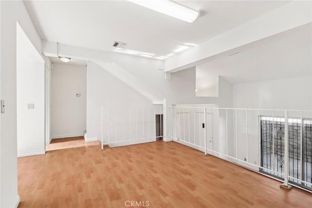 spare room with wood-type flooring and lofted ceiling with beams