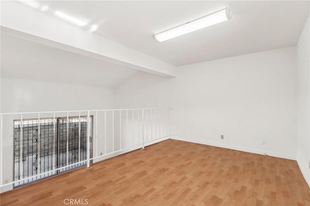 unfurnished room with wood-type flooring and vaulted ceiling with beams