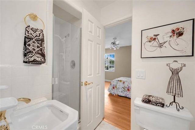 bathroom with ceiling fan, wood-type flooring, an enclosed shower, and toilet