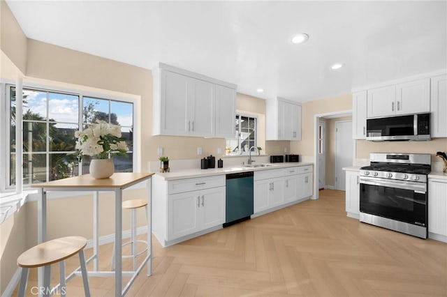 kitchen featuring light parquet floors, appliances with stainless steel finishes, white cabinetry, and sink