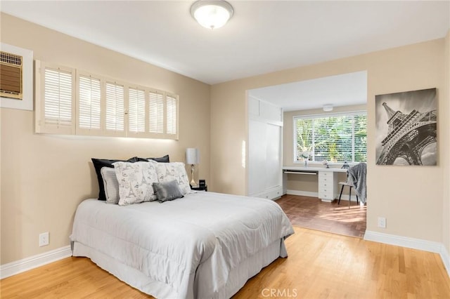 bedroom with wood-type flooring and a wall mounted air conditioner